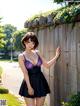 A woman in a purple dress leaning against a wooden fence.