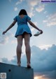 A woman in a blue dress standing on top of a concrete wall.