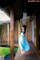 A woman in a blue and white dress standing on a wooden walkway.